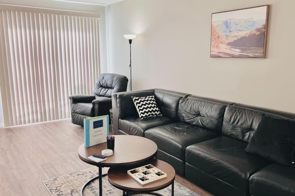 ein Wohnzimmer mit einem schwarzen Ledersofa und einem Tisch in der Unterkunft Spacious 2-bedroom apartment in Camrose