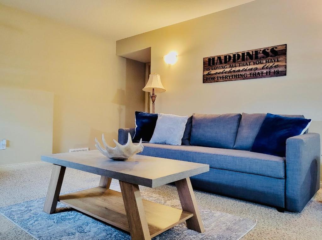 uma sala de estar com um sofá azul e uma mesa de centro em Spacious Basement suite em Camrose