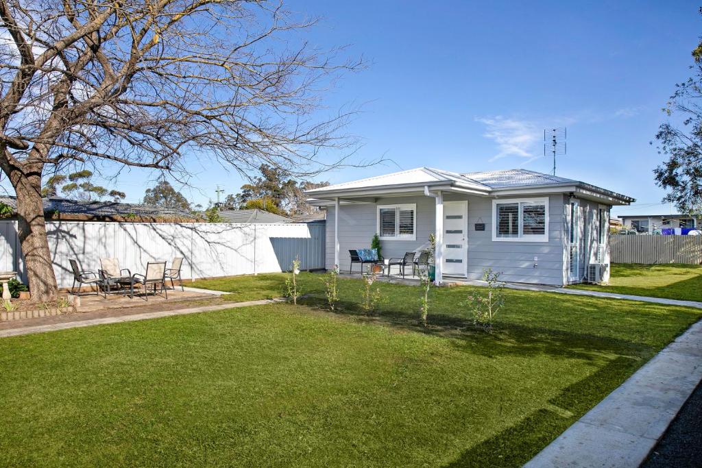 a small white house with a yard at Camellia Cottage in Berrima