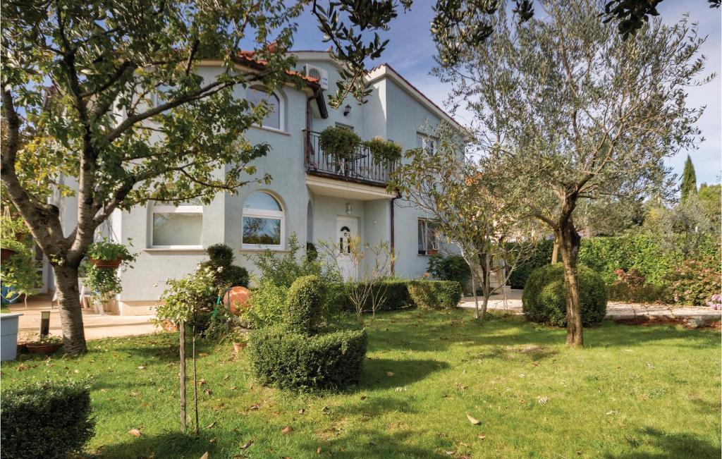 ein großes weißes Haus mit Bäumen im Hof in der Unterkunft 1 Bedroom Gorgeous Apartment In Fazana in Fažana