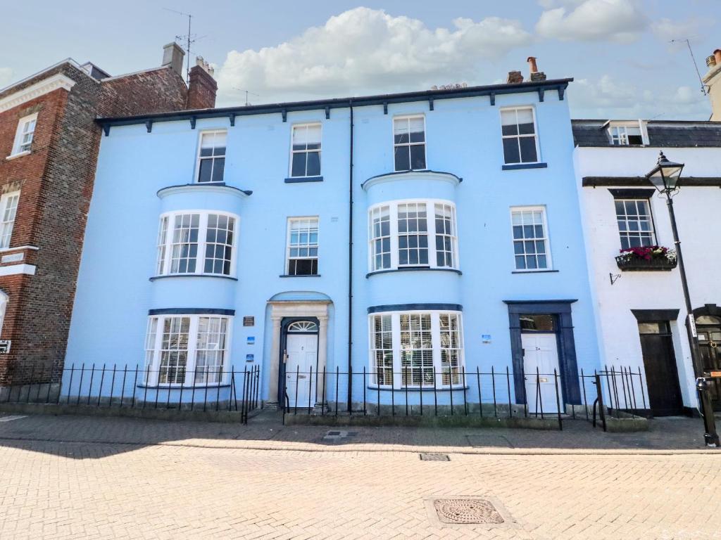 ein blaues Haus mit weißen Fenstern und einem Zaun in der Unterkunft Tradewinds in Weymouth