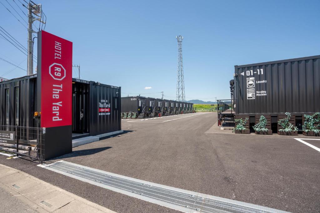 una fila de contenedores de transporte en un estacionamiento en HOTEL R9 The Yard Honjo en Honjo