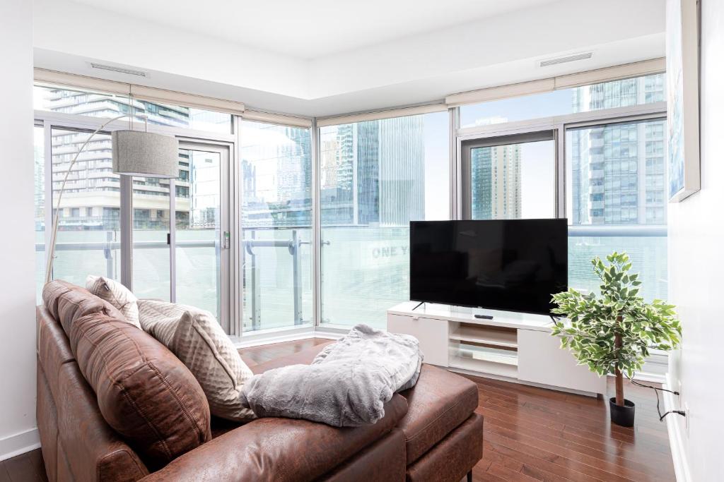 a living room with a couch and a flat screen tv at Downtown Toronto condo mins from Scotiabank arena, TIFF, CN TOWER, UNION, MTCC in Toronto