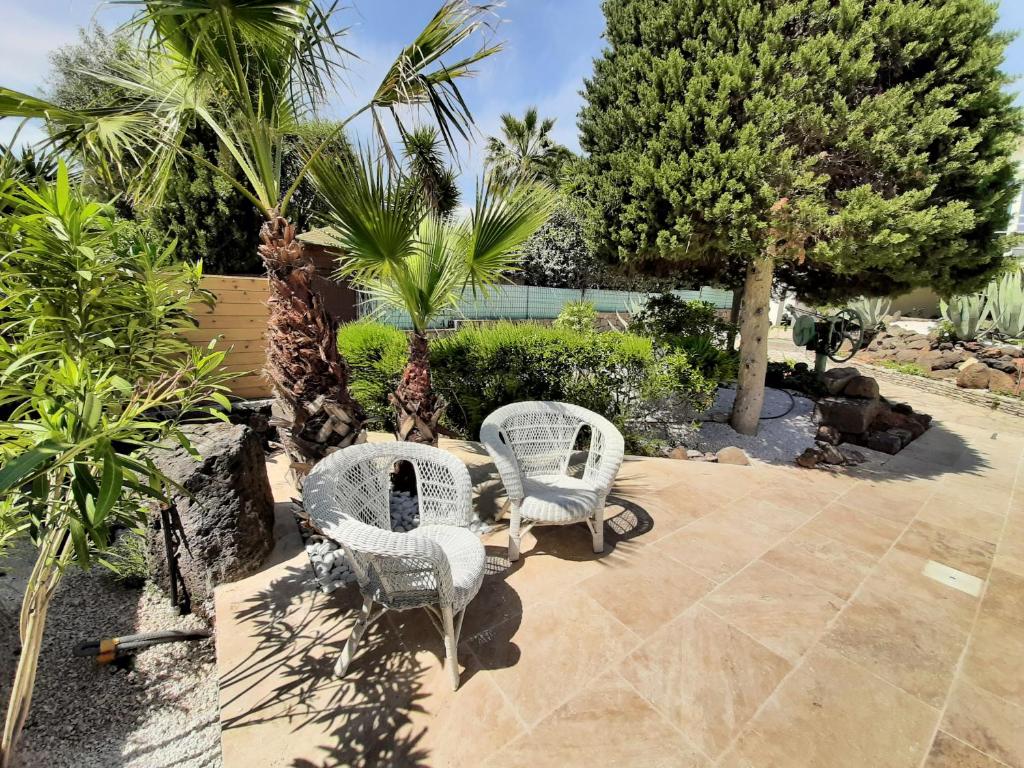 two white chairs sitting on a patio with palm trees at VILLA RASOA chambre LIBELLULE in Cap d&#39;Agde