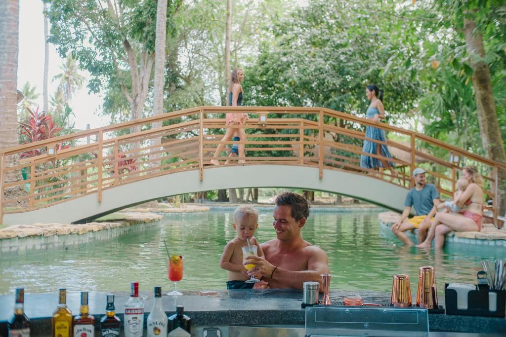 un hombre y un niño en el agua bajo un puente en Tropik Resort Lombok, en Selong Belanak