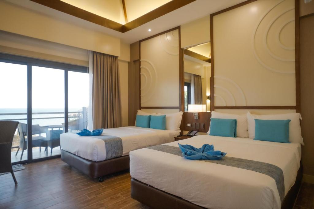 ein Hotelzimmer mit 2 Betten mit blauen Bogen in der Unterkunft Parklane Bohol Resort and Spa in Anda