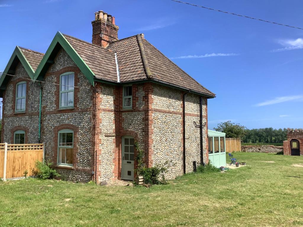 an old brick house on a grass field at Owl Cottage in Norwich