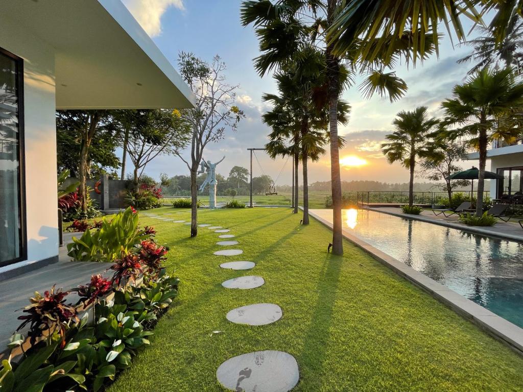 un jardín con rocas en el césped junto a una piscina en The Valerian Villa Ubud, en Ubud