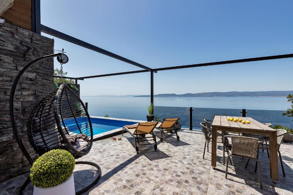 een patio met een tafel en stoelen en uitzicht op het water bij Villa Iva in Pisak