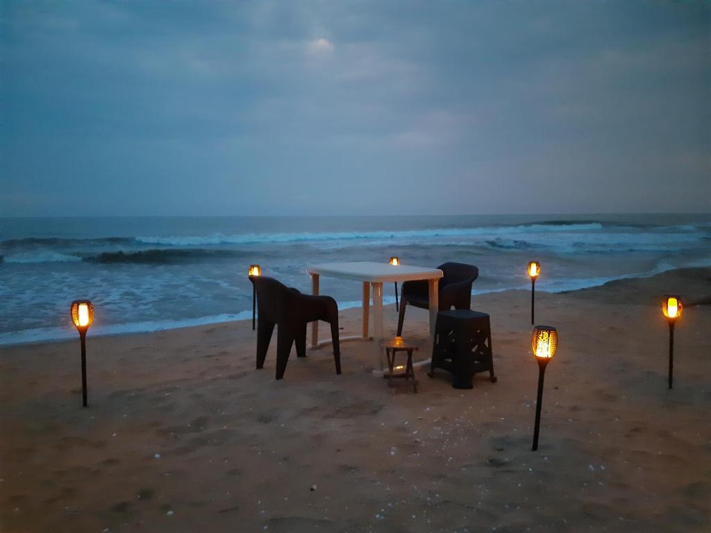 - une table et des chaises sur la plage la nuit dans l'établissement The Camp Club Beach Villa, à Payyannūr