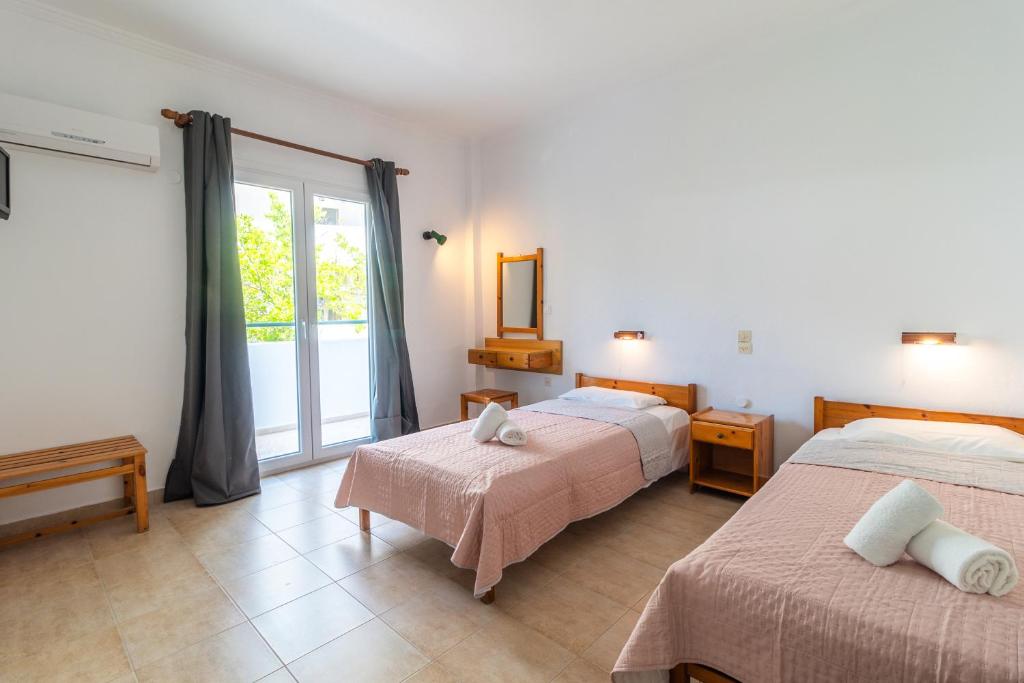 1 dormitorio con 2 camas y ventana en Kantaros Apartments, en Ýpsos