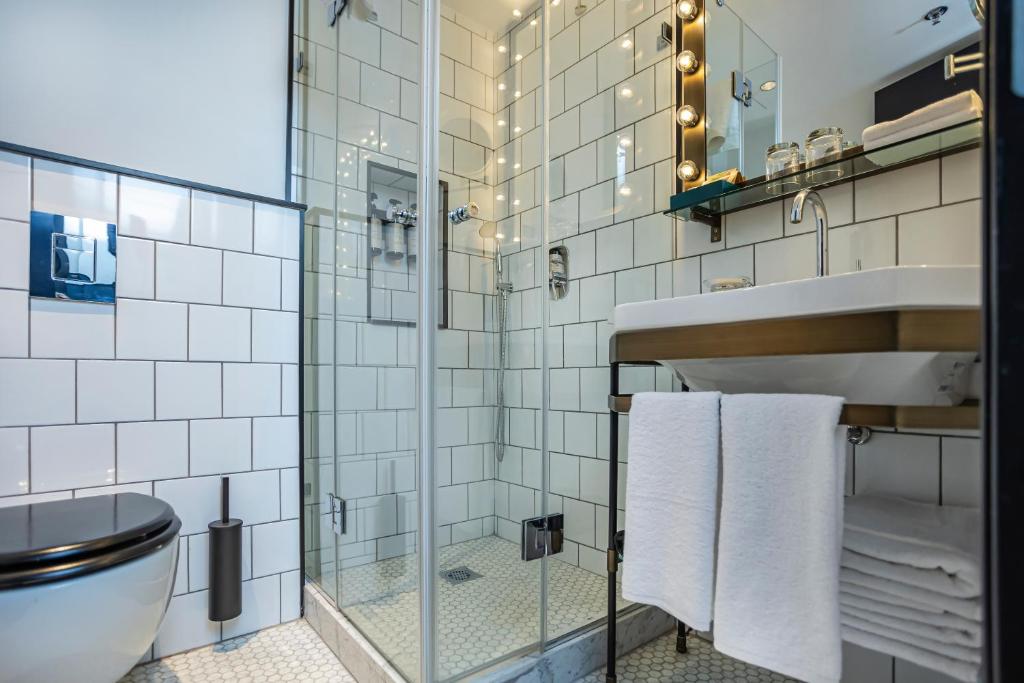 a bathroom with a toilet and a glass shower at Backstage Hotel - an Atlas Boutique Hotel in Tel Aviv