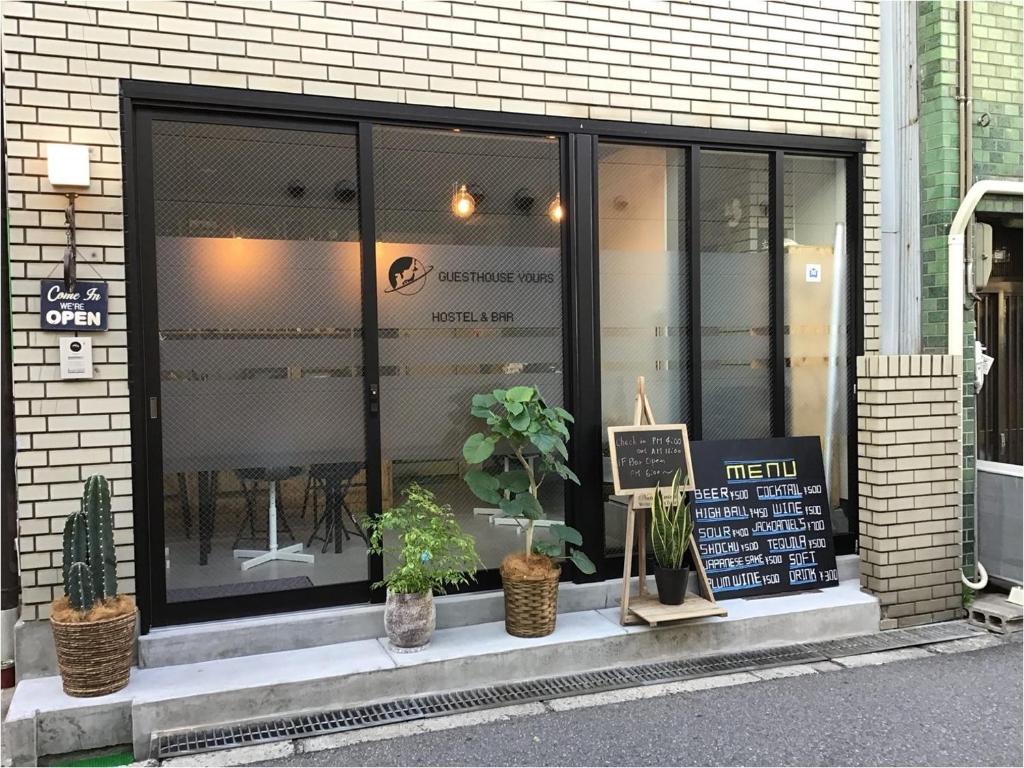 a store window with potted plants in front of it at Guesthouse Yours in Osaka