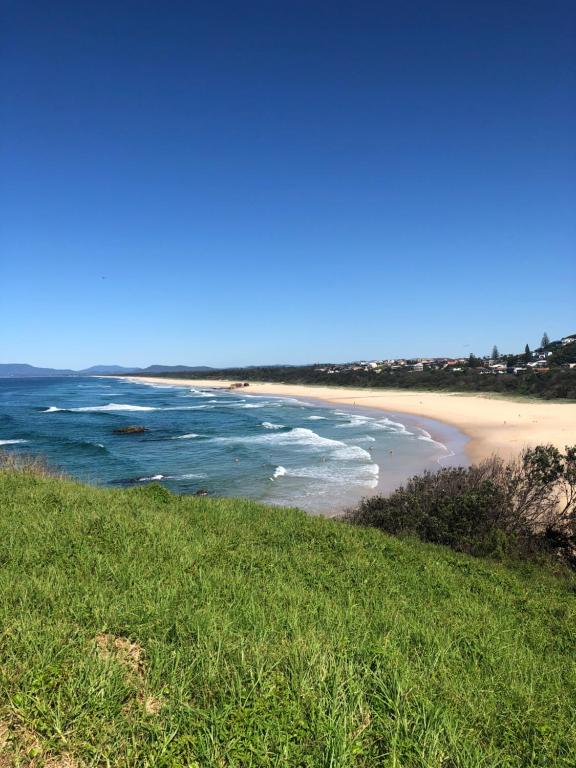 uma vista para uma praia a partir de uma colina relvada em Fi's Beach Pad em Port Macquarie