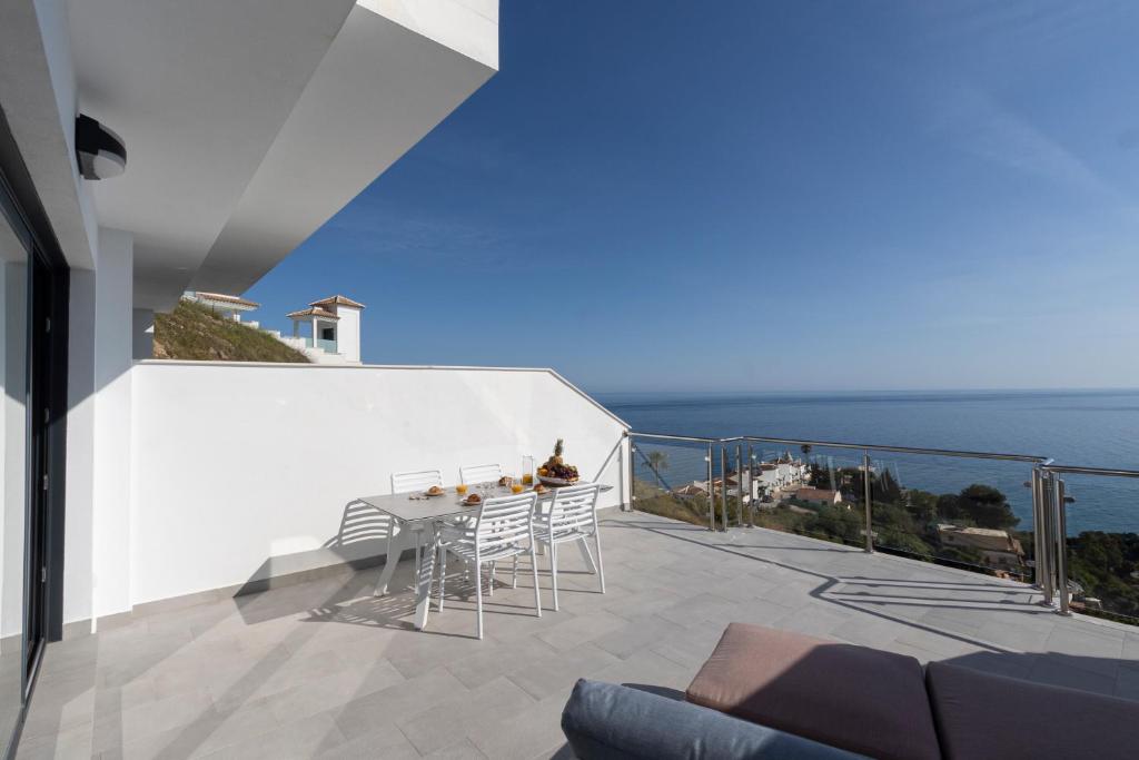 uma varanda com uma mesa e cadeiras e o oceano em Apartamento Terraza al Mar, Nerja em Nerja