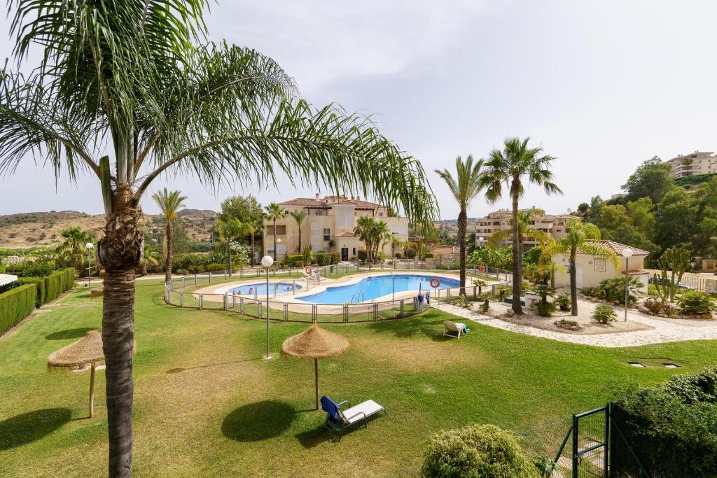 a resort with a swimming pool and palm trees at La cala hills in Mijas Costa