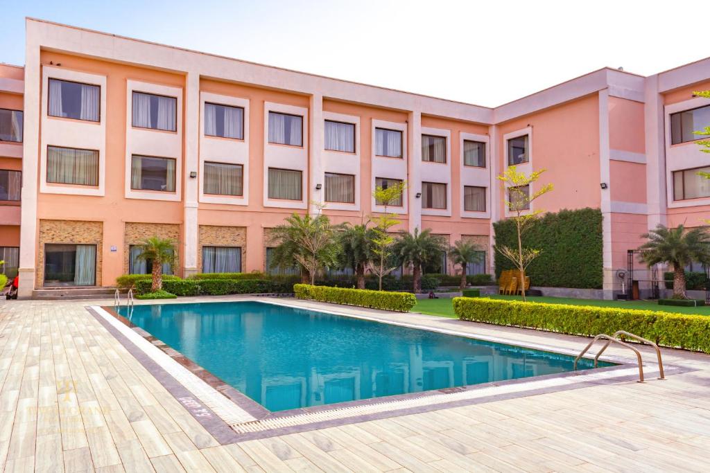 a building with a swimming pool in front of a building at Tivoli Grand Resort in New Delhi