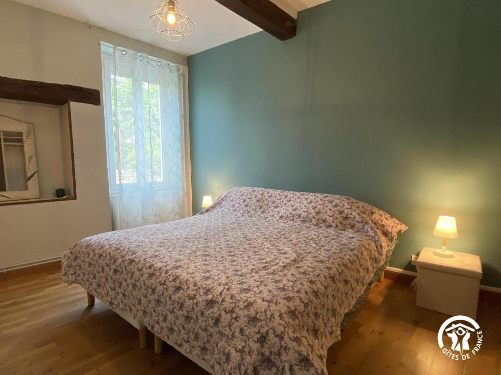 a bedroom with a bed and a window and two lamps at Le Georges V in Alzonne