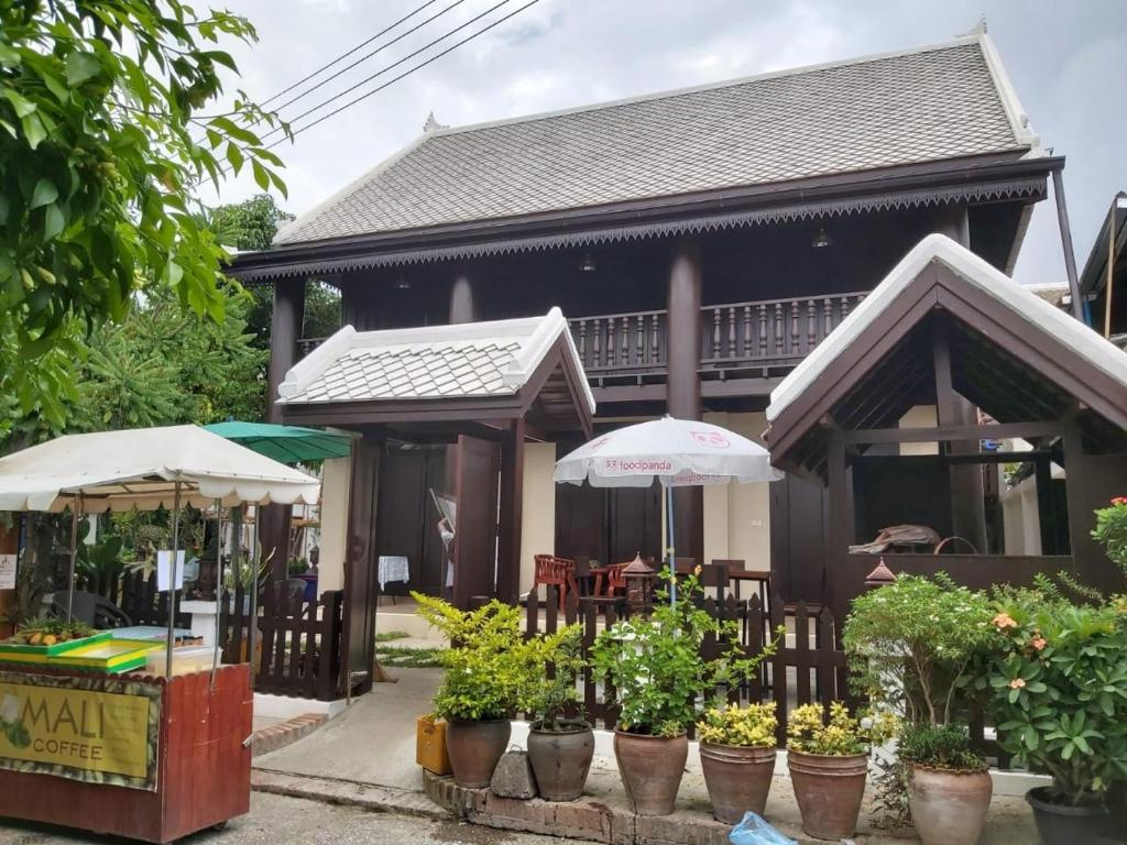 a house with umbrellas and plants in front of it at Mali House in Luang Prabang