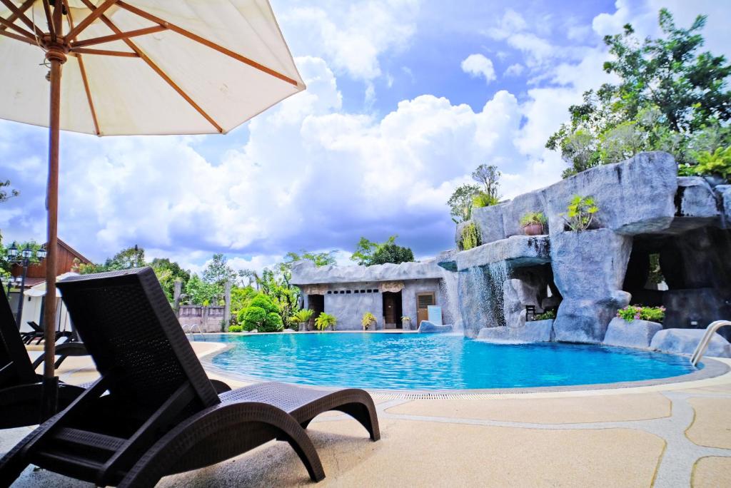 uma piscina de resort com um guarda-sol e uma cadeira reclinável em Rnana Grand em Phangnga