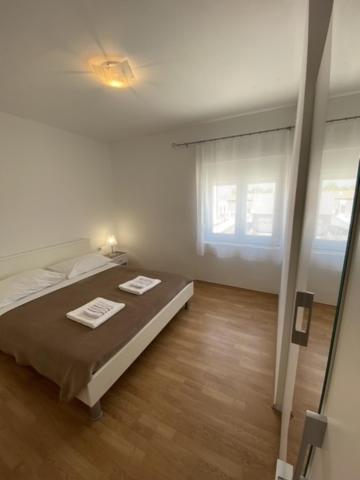 a white bedroom with a bed and a window at Apartments Zvonimir in Privlaka