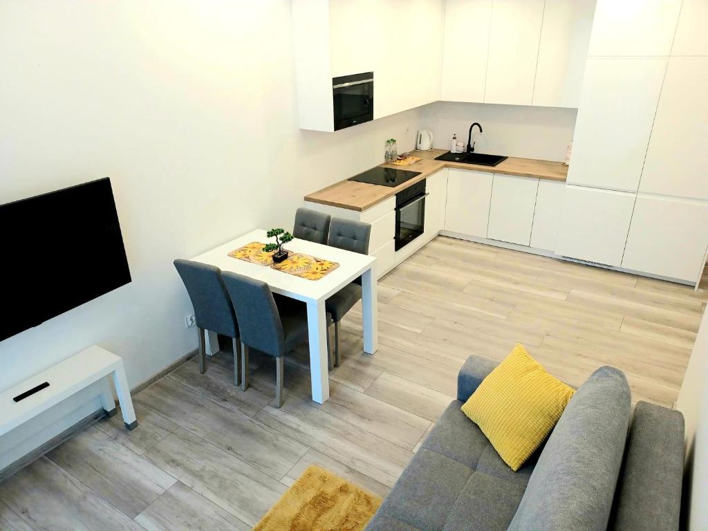 a kitchen and a living room with a table and a couch at AJP Nova3 Lux Apartament in Szczecin