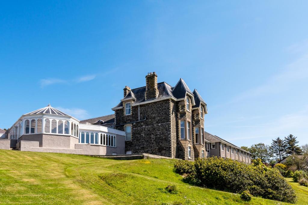 uma casa velha numa colina relvada em Fernhill Hotel em Portpatrick