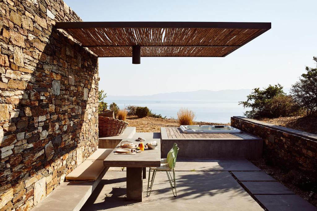 eine Terrasse mit einem Tisch und einer Ziegelwand in der Unterkunft Hidden Retreats Kythera in Platia Ammos