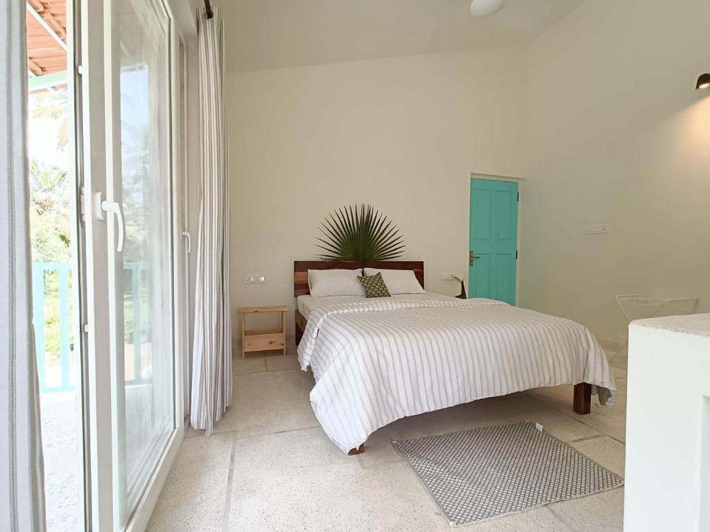 a white bedroom with a bed and a window at Beseco Bed and Breakfast in Benaulim