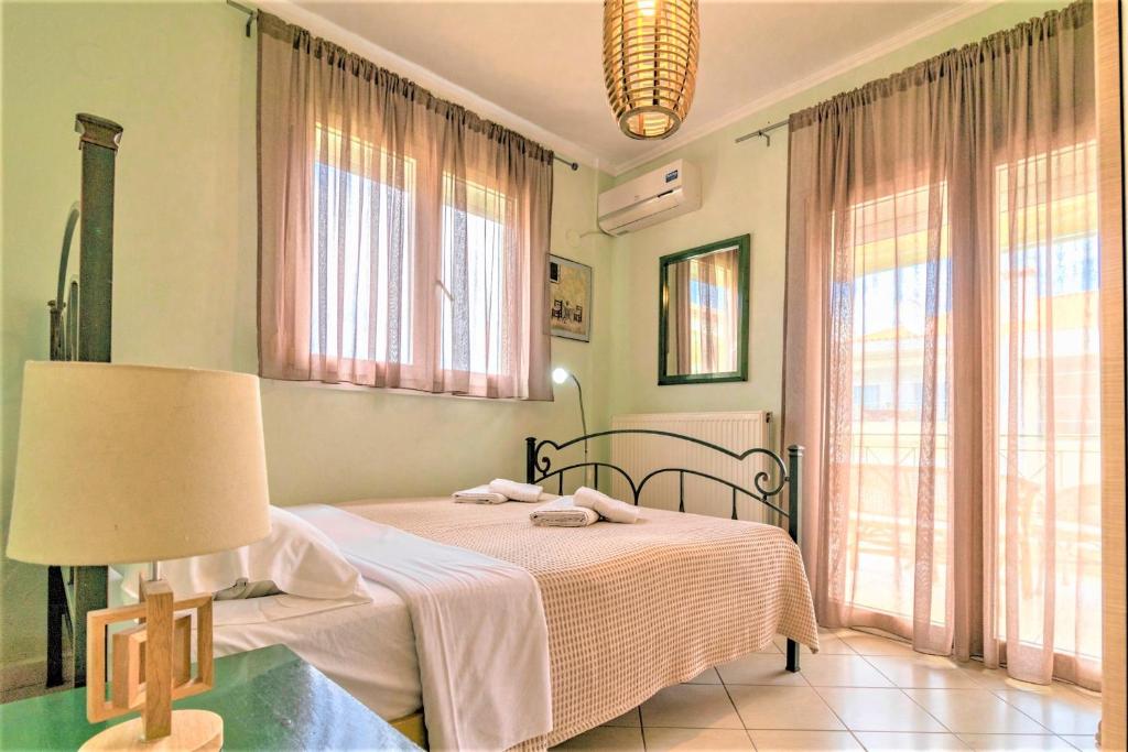 a bedroom with a bed and a lamp and windows at Casa Mameli Αpartments in Kallithea Halkidikis