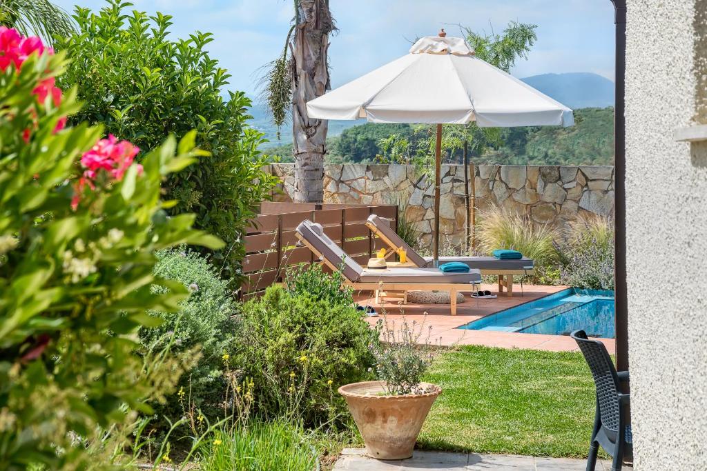 un patio trasero con piscina y sombrilla en Yiannis Cottage, en Spiliá