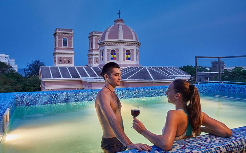 ポンディシェリにあるVILLA DU OCEANのワインを飲みながらスイミングプールに座る男女