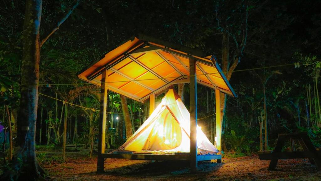 a lit up tent in a forest at night at Jimmy Explorer Campsite and Dive Center in Lanyu