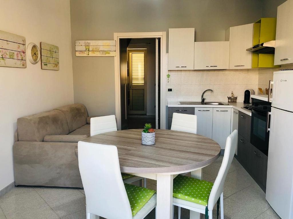 cocina y comedor con mesa de madera y sillas en La casa di Alice è un bilocale luminoso e felice, en Porto Empedocle