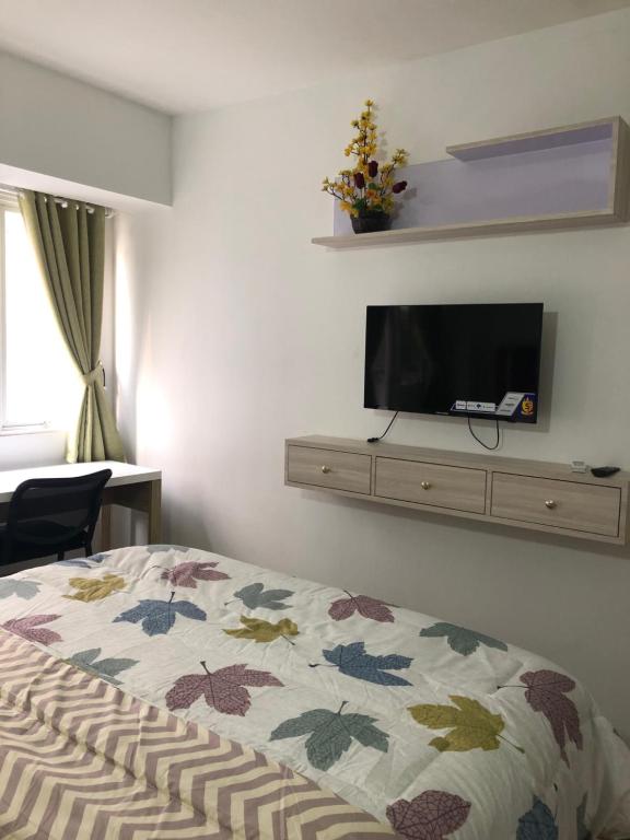 a bedroom with a bed and a tv on a wall at Apartment Grand Sentraland Karawang Manage by Laguna Room in Karawang