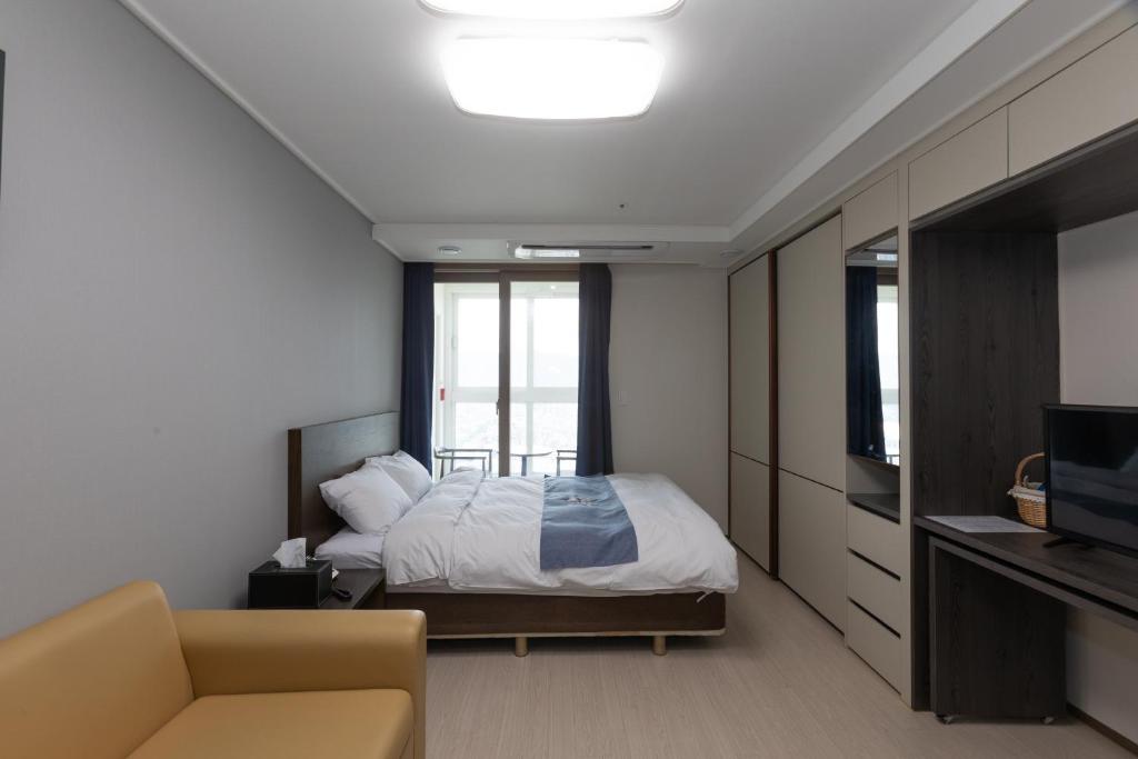 1 dormitorio con cama, sofá y TV en Golden Planet Hotel en Icheon