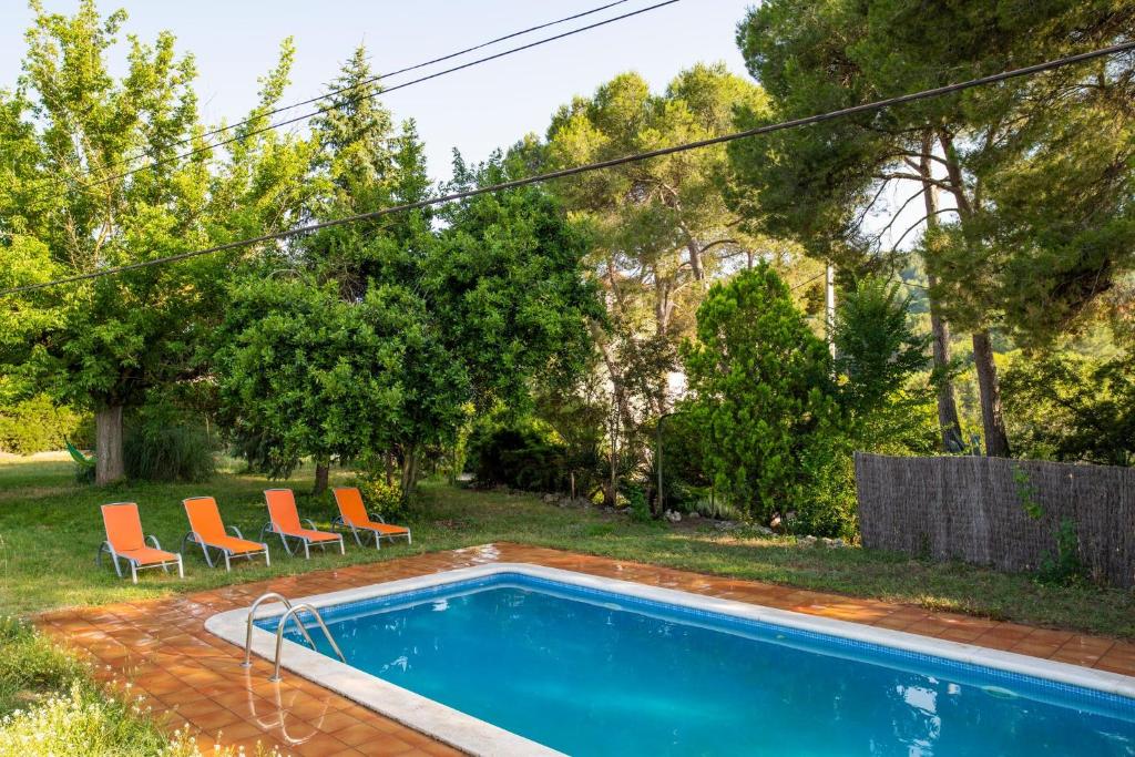 una piscina en un patio con 2 sillas en Masia Can Comas, en Sant Pere de Riudebitlles