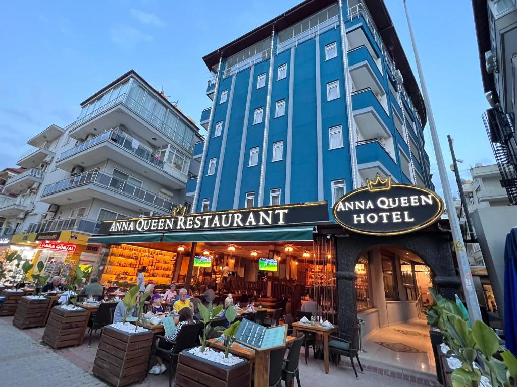 a restaurant with people sitting at tables in front of a building at Anna Queen Hotel in Alanya