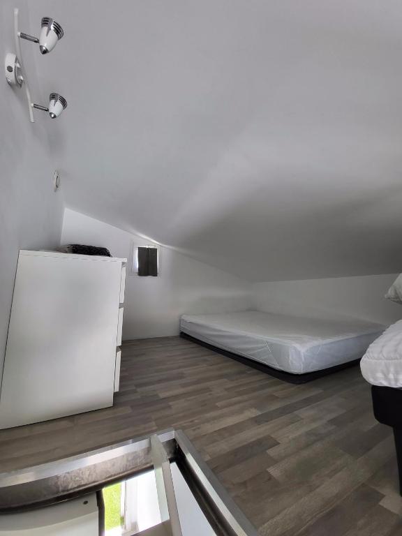Habitación blanca con cama y suelo de madera. en Studio mezzanine Saint Bres. 20min de Montpellier, en Saint-Brès