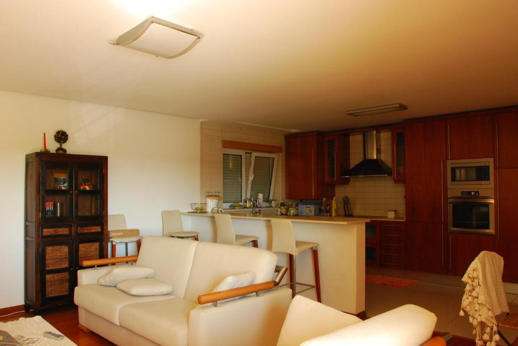 a living room with a white couch and a kitchen at AH Leiria apartment in Leiria