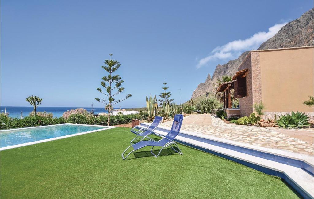 a pair of blue chairs sitting on a lawn next to a swimming pool at 4 Bedroom Cozy Home In Custonaci in Custonaci