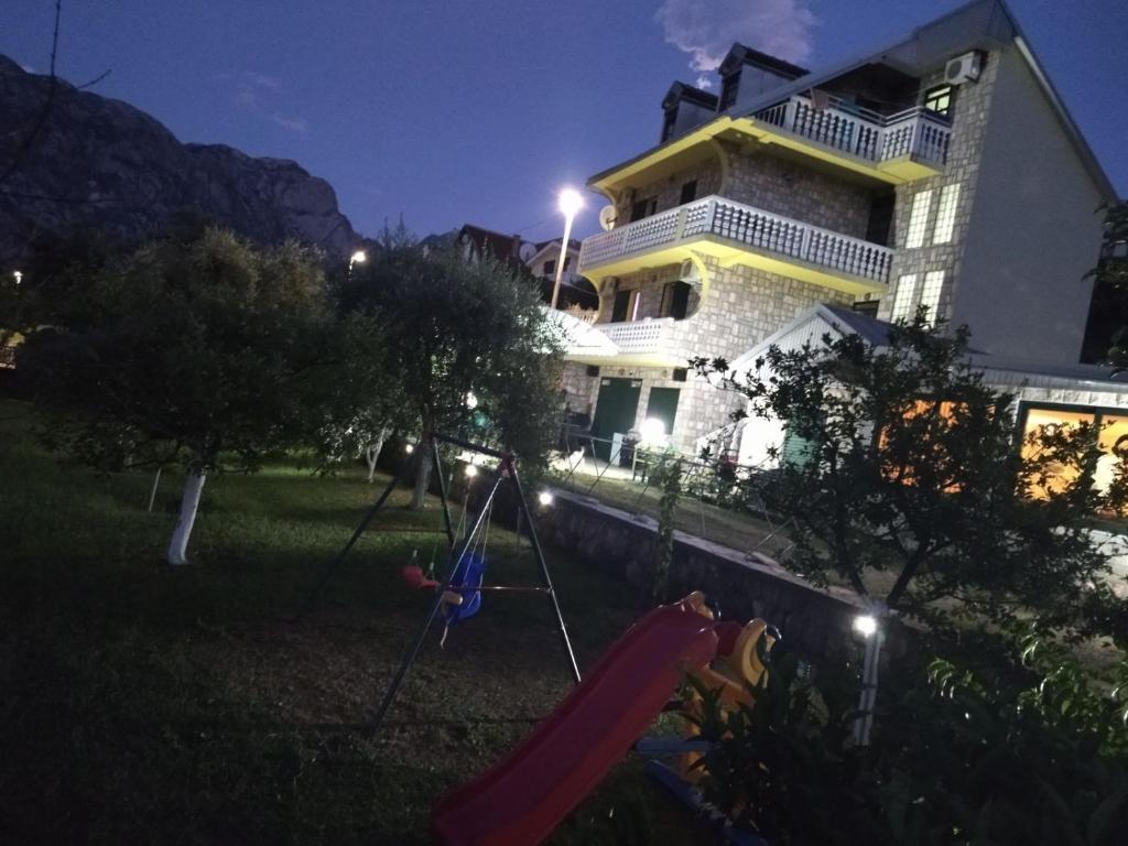 a house with a playground in the yard at night at Apartment Ksenija in Kotor