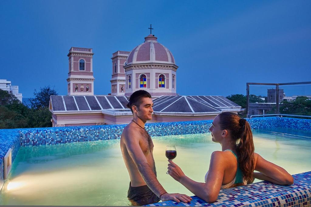 a man and woman sitting in the swimming pool with a glass of wine at VILLA DU OCEAN in Puducherry