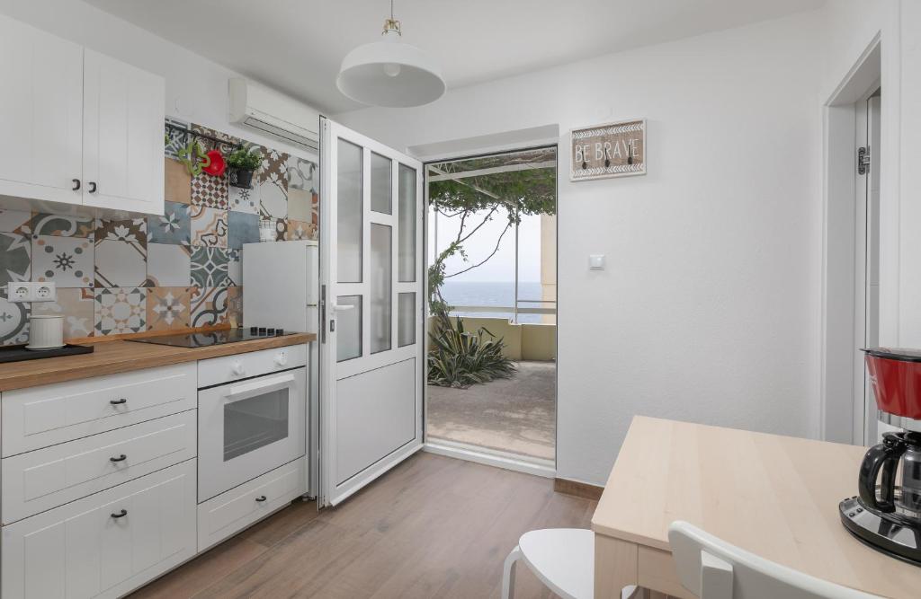 uma cozinha com armários brancos e uma porta que leva a um pátio em La casa di Nonno em Milna