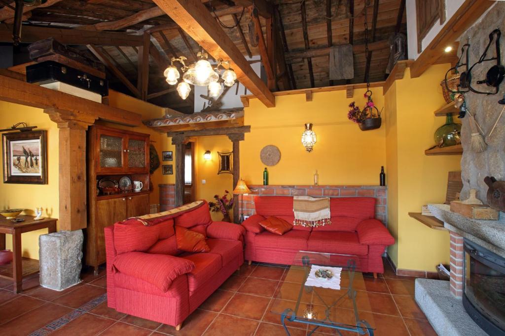 sala de estar con sofás rojos y chimenea en Casa rural El Leñador en Ávila