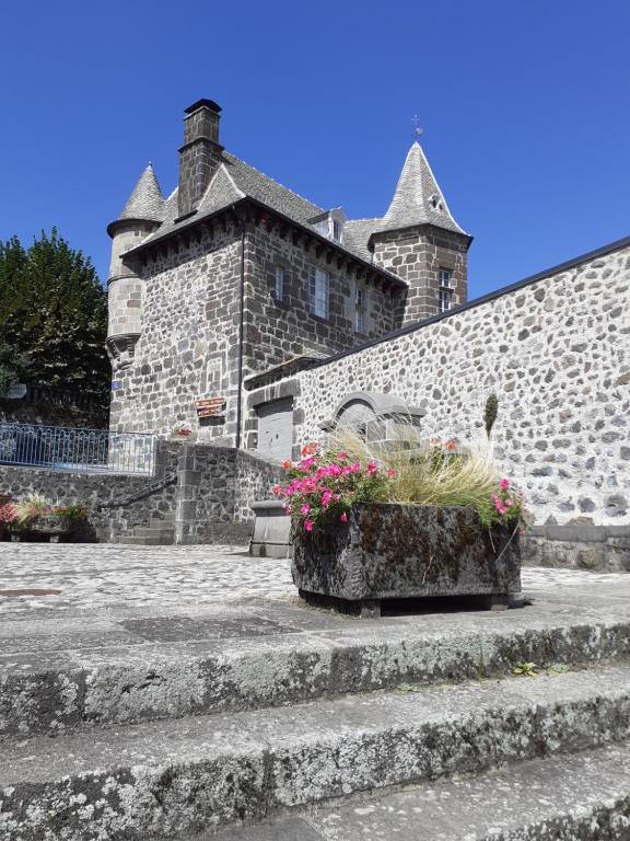 a stone building with some flowers in a pot at Maison du Chevalier des Huttes - Table et Chambres d'hôtes in Vic-sur-Cère