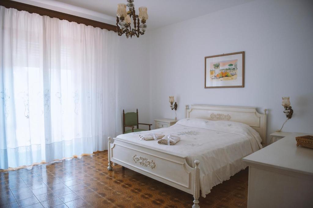 ein weißes Schlafzimmer mit einem Bett und einem Kronleuchter in der Unterkunft Il Viaggiatore Errante in Fondi