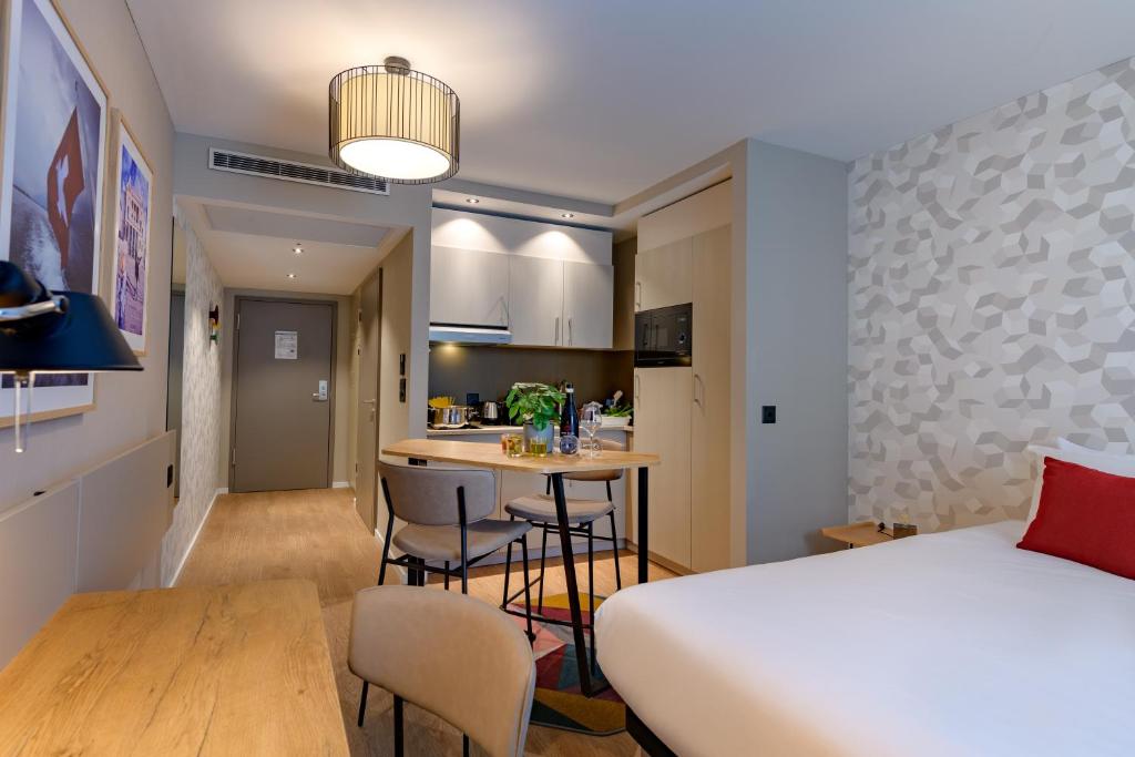 a room with a bed and a kitchen with a table at Aparthotel Adagio Zurich City Center in Zurich