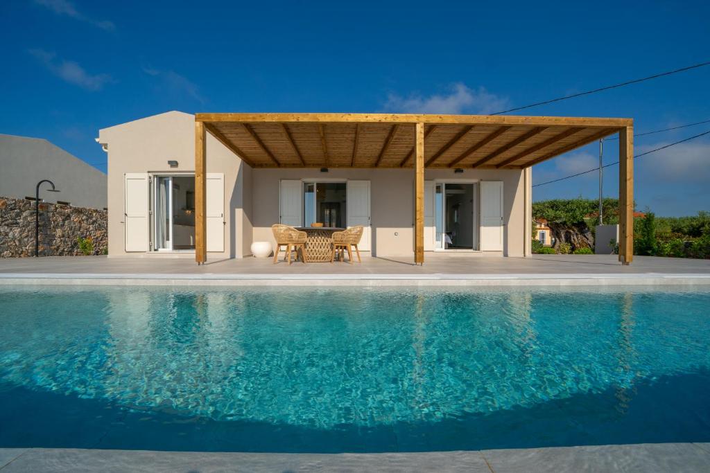 a villa with a swimming pool in front of a house at Summer Breeze Villa in Tzamarelláta