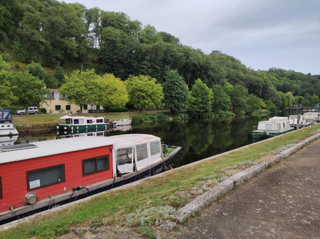 a red and white boat parked next to a river at LES GÎTES CELTIQUES DU PÈRE NICOLAS in Plumeliau Bieuzy